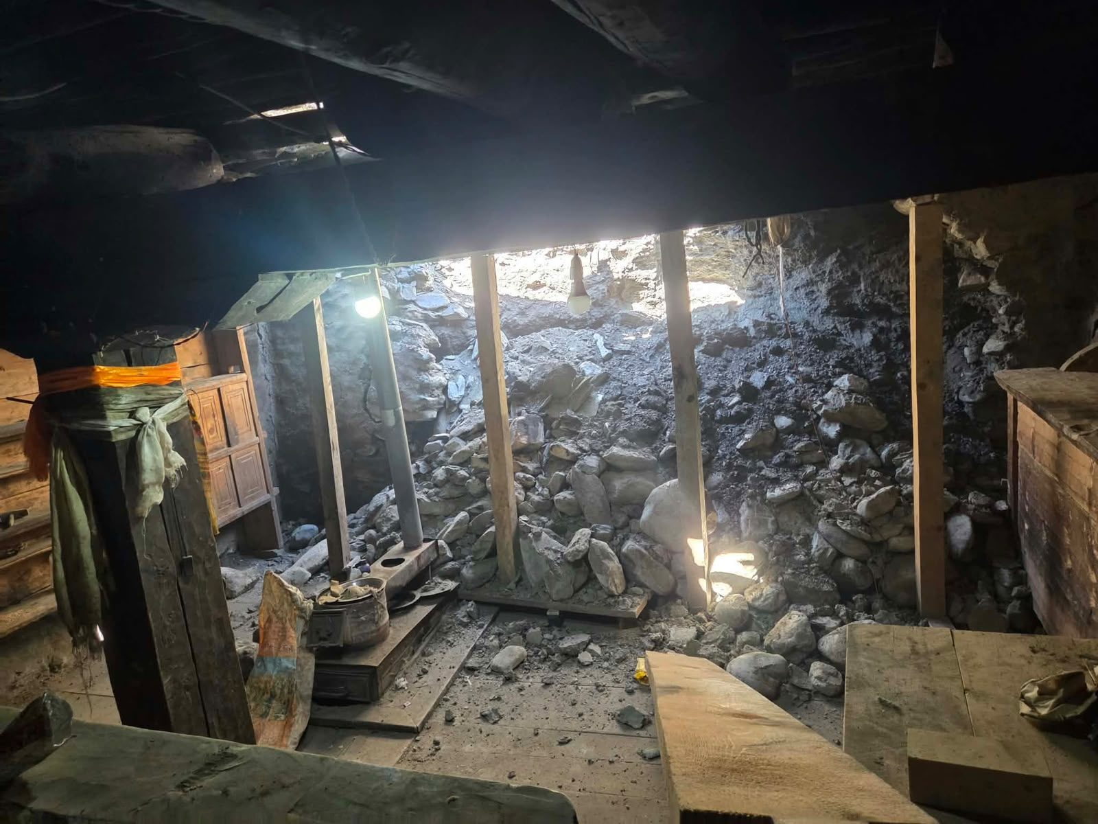 Inside the house: rocks and earth fill the room behind the wooden posts
